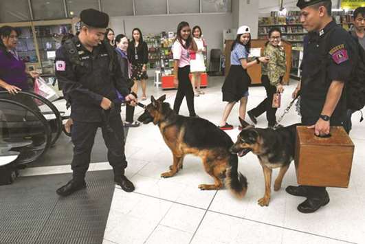 Government employees watch police dogs belonging to Royal Thai police special K-9 unit demonstrate skills to detect bombs and illegal drugs at a government complex in Bangkok yesterday.