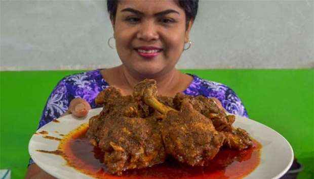 An Indonesian food vendor holds a plate of chicken rendang at a restaurant in Pekanbaru.