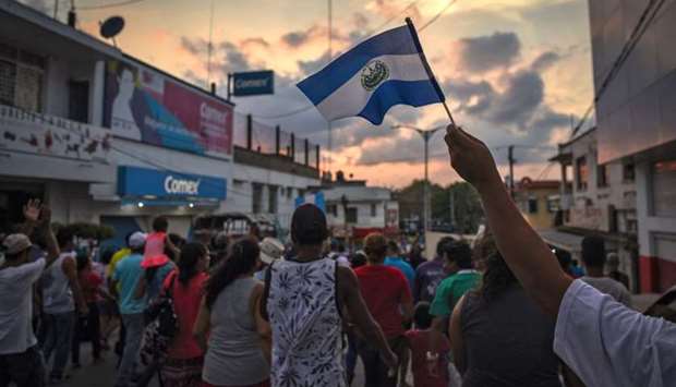 A migrant -alongside other Central Americans taking part in a caravan called ,Migrant Viacrucis, towards the United States- flutters a Guatemalan national flag during a march to protest against US President Donald Trump's policies in Matias Romero, Oaxaca State, Mexico.