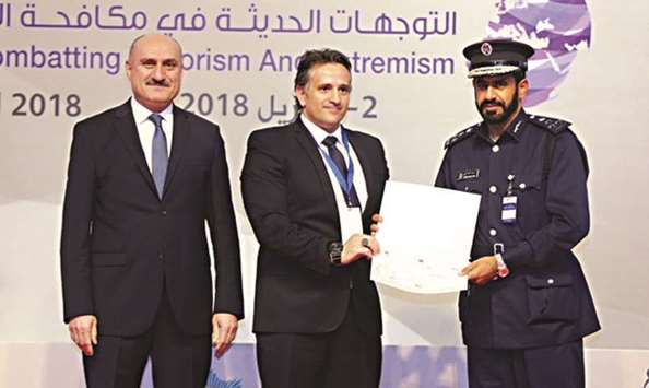 A Qatar Police Academy official receiving a certificate from INTERPA at conference.