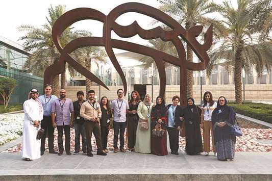 Members of International Artists of Doha standing by the Desert Horse Art Piece at HIA.