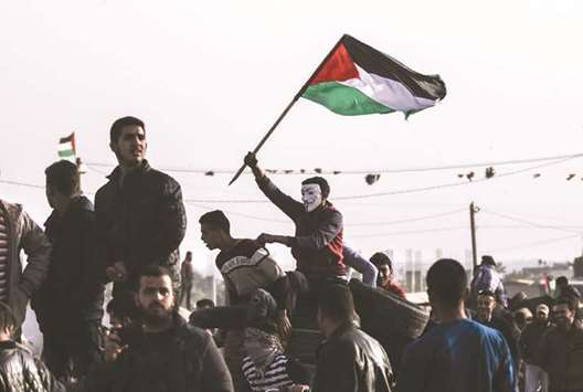 A Palestinian protester waves his national flag at the site of a tent protest in support of  refugees returning to lands they fled or were expelled from during the war surrounding Israelu2019s creation, near the border, east of Khan Yunis, in the southern Gaza Strip, yesterday.