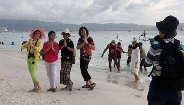 Tourists pose for photos along a beach on Boracay island in Malay town in central Philippines.