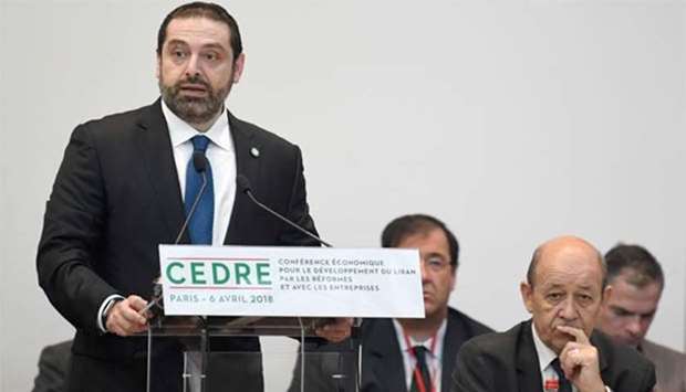 Lebanese Prime Minister Saad Hariri delivers a speech as French Foreign Minister Jean-Yves Le Drian listens during the conference for international donors and investors to support Lebanon's economy, in Paris on Friday.