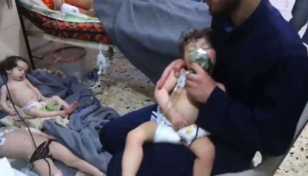 An image grab taken from a video released by the Syrian civil defence in Douma shows an unidentified volunteer holding an oxygen mask over a child's face at a hospital following a reported chemical attack on the rebel-held town.
