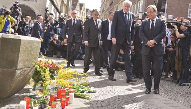German Interior Minister Horst Seehofer (second right) and State leader in North Rhine-Westphalia Armin Laschet (right) pay their respect yesterday at a memorial shift at the square where a man ploughed with a van into an open-air restaurant, killing two people a day earlier in Muenster.