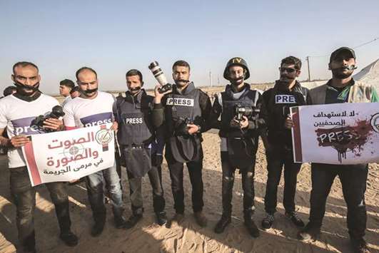 Palestinian journalists tape themselves during a protest against the killing of fellow journalist Yasser Murtaja, near the Israel-Gaza border, in Rafah in the southern Gaza Strip, yesterday.