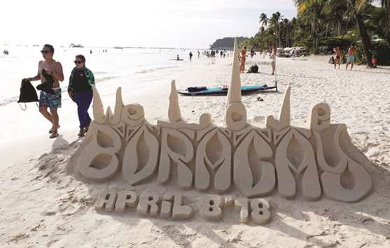Tourists walk near a sand sculpture along the beach of Boracay.