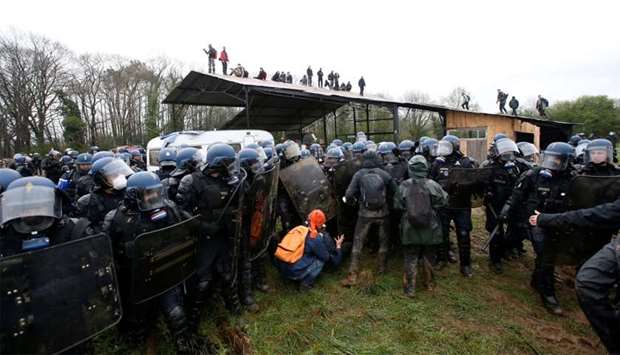 French gendarmes block a small group of protesters as others take position on the roof of a structure during an evacuation operation in the zoned ZAD (Deferred Development Zone) in Notre-Dame-des-Landes