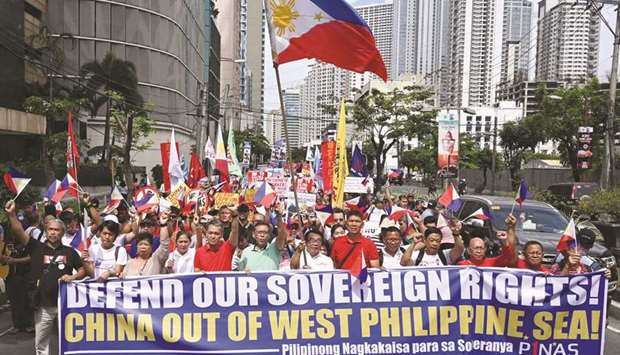 Anti-China protesters carrying national flags and placards march towards the Chinese consular office in a protest in the financial district of Manila, yesterday.
