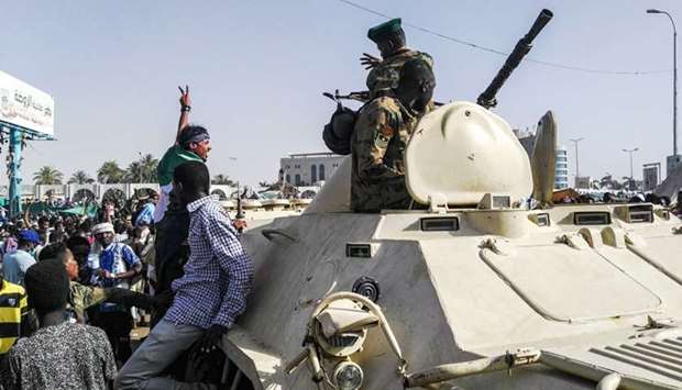 Sudanese protesters salute a military armoured vehicle as they gather during a demonstration in front of the military headquarters in the capital Khartoum.