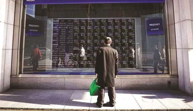 A pedestrian looks at an electronic stock board outside a securities firm in Tokyo (file). The Topix index is trading at the lowest level relative to the S&P 500 since Prime Minister Shinzo Abe took office near the end of 2012, highlighting ebbing enthusiasm for Japanese stocks among overseas investors, according to Mizuho Securities.