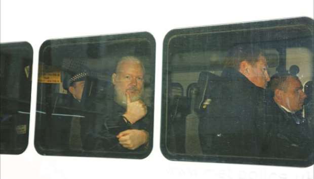 WikiLeaks founder Julian Assange flashes a thumbs-up from a police van, after he was arrested by police, in London yesterday.