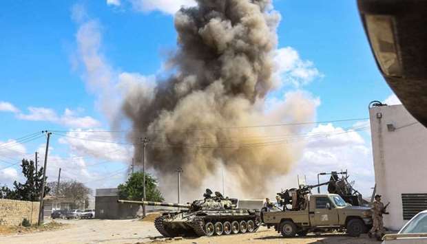 A smoke plume rising from an air strike behind a tank and technicals (pickup trucks mounted with turrets) belonging to forces loyal to Libya's Government of National Accord (GNA), during clashes in the suburb of Wadi Rabie