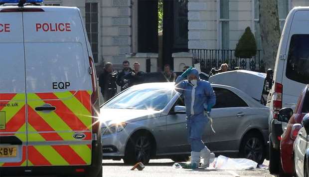 Police forensics officer works at the site where police fired shots after a vehicle rammed the parked car of Ukraine's ambassador, outside the Ukrainian embassy in London