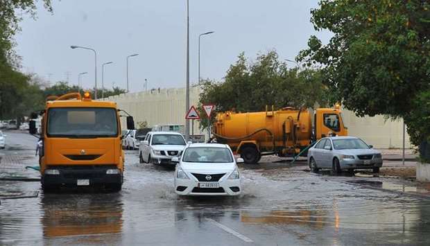 A car makes its way through a waterlogged road as tankers line up to clear the rainwater. PICTURE: Nasar K Moideen