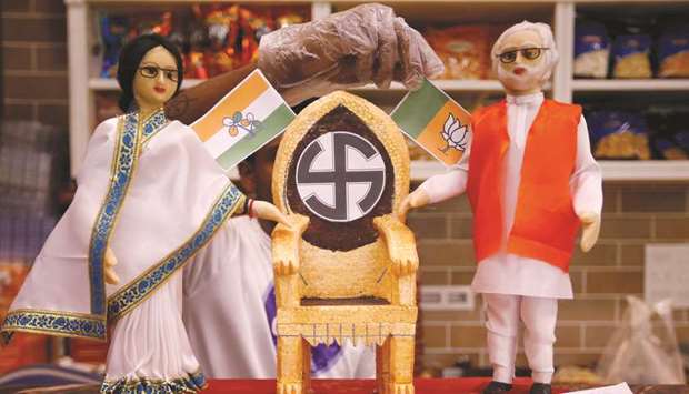 A confectioner decorates a chair beside the models, made out of sweets, depicting West Bengal Chief Minister Mamata Banerjee and Prime Minister Narendra Modi at a sweets shop ahead of the second phase of general election, in Kolkata yesterday.