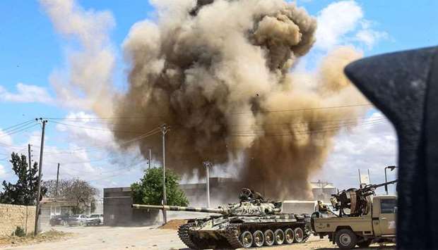 A smoke plume rising from an air strike behind a tank and technicals (pickup trucks mounted with turrets) belonging to forces loyal to Libya's Government of National Accord (GNA), during clashes in the suburb of Wadi Rabie