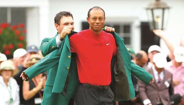 Last yearu2019s Masters champion Patrick Reed (left) puts the Green Jacket on for Tiger Woods after the latter won the 2019 edition in Augusta, United States, yesterday. (AFP)