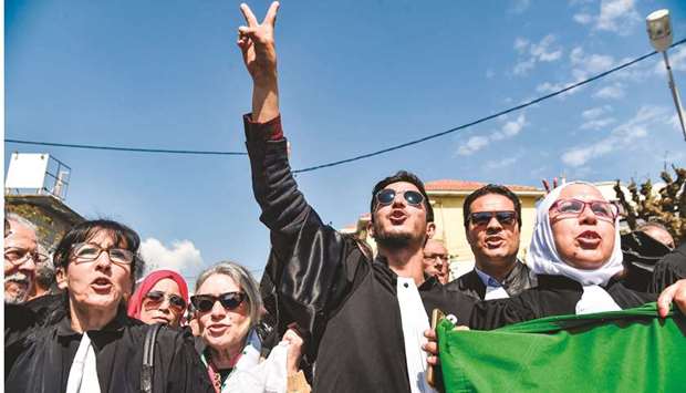 Algerian lawyers and judges chant slogans and raise a national flag as they gather for a demonstration for the independence of the judiciary outside the Justice Ministry headquarters in the capital Algiers on April 13.