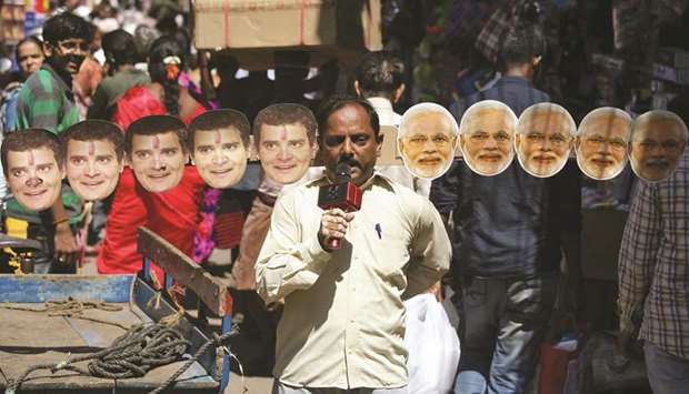 Anand Kumar Bowmick, a social activist, carries masks of Prime Minister Narendra Modi and Congress president Rahul Gandhi through a busy street as he appeals people to vote in the second phase of general election, in Chennai yesterday.