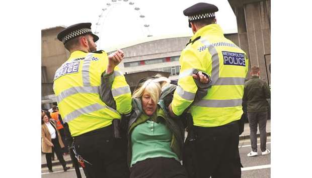 Police officers detain a climate change activist at Waterloo Bridge during the Extinction Rebellion protest in London yesterday.