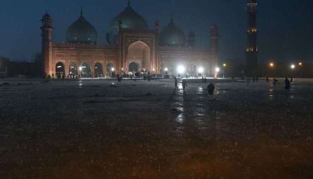 People arrive to pray at the historical Badshahi Mosque during heavy rain in Lahore yesterday.