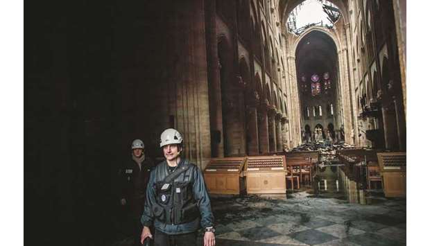 Staff members walk inside the Notre-Dame Cathedral, in the aftermath of a fire that devastated the building.