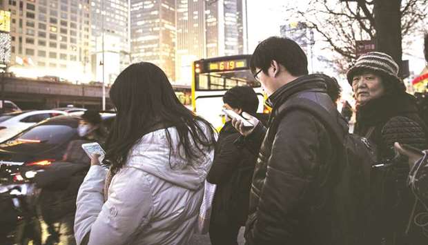 Commuters using smartphones stand in line at a bus station in Beijing. Chinau2019s stimulus measures will shore up economic growth this year and next but may undermine the countryu2019s drive to control debt and worsen structural distortions over the medium term, the OECD said in a report yesterday.