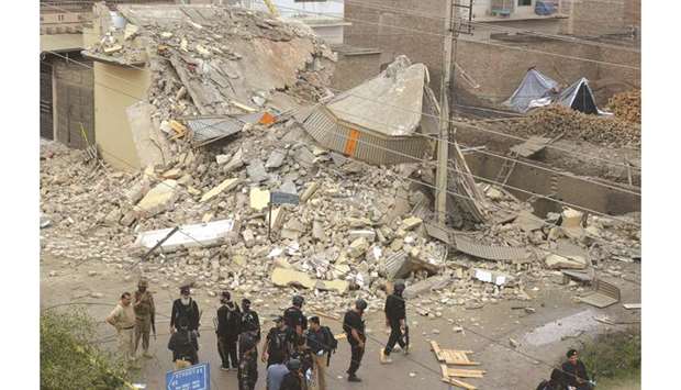 Security forces gather near the demolished building during an operation in Peshawar.