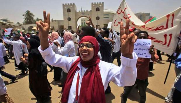 Sudanese demonstrators wave signs as they continue to protest outside the army complex in the capital Khartoum
