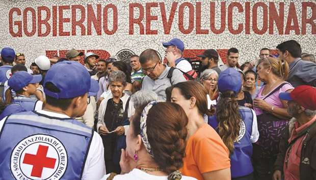 People queue to receive drums to collect water and water purification tablets from members of the Venezuelan Red Cross in Catia neighbourhood in Caracas, Venezuela, on April 16.  The first shipment of Red Cross humanitarian aid arrived in crisis-wracked Venezuela on Tuesday following approval from President Nicolas Madurou2019s government, the organisation confirmed. Venezuela is now experiencing a classic populist collapse.