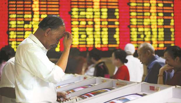 Investors look at computer screens showing stock information at a brokerage house in Shanghai. Sponsors and their units should hold their stakes for at least 24 months, the Shanghai Stock Exchange said in a statement on Tuesday, an arrangement virtually unheard of in global markets.