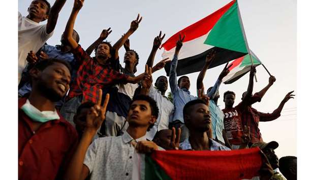 Sudanese demonstrators make victory signs and wave Sudanese flags as they protest in front of the Defence Ministry in Khartoum, yesterday.