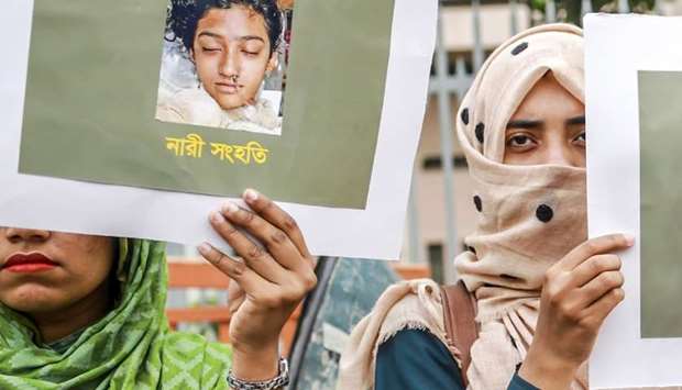 In this photo taken on April 12, 2019 Bangladeshi women hold placards and photographs of schoolgirl Nusrat Jahan Rafi at a protest in Dhaka, following her murder by being set on fire after she had reported a sexual assault