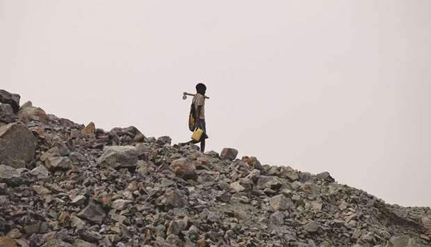 A boy leaves the hill after searching for gold in discarded waste rock from the North Mara mine operated by African Barrick Gold, near Nyangoto, Tanzania (file). The International Monetary Fund said that Tanzaniau2019s economy is being harmed by the governmentu2019s u201cunpredictable and interventionist policiesu201d in a report whose release the East African country has blocked.