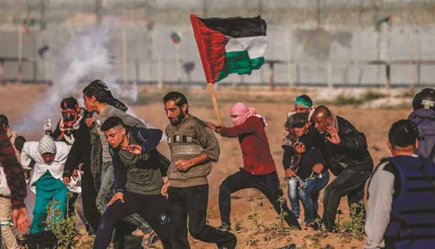 Palestinians react to teargas canisters fired by Israeli forces during clashes following a demonstration by the border fence, east of Gaza City, yesterday.