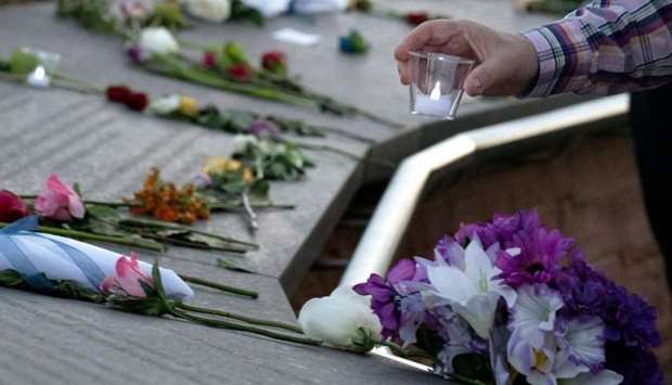 A visitor places a candle among flowers at the Columbine Memorial at Clement Park in Littleton, Colorado, during a community vigil for the 20th anniversary of the Columbine High School mass shooting