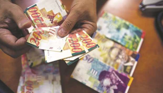 An employee counts Israeli shekel notes at a bank branch in Tel Aviv (file). The shekelu2019s weakening against the dollar and euro, along with rising inflation, added to Israelu2019s debt burden last year.