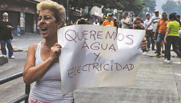 A woman holds a placard reading u2018We Want Water and Electricityu2019 during a protest at Fuerzas Armadas Avenue in Caracas on Sunday.