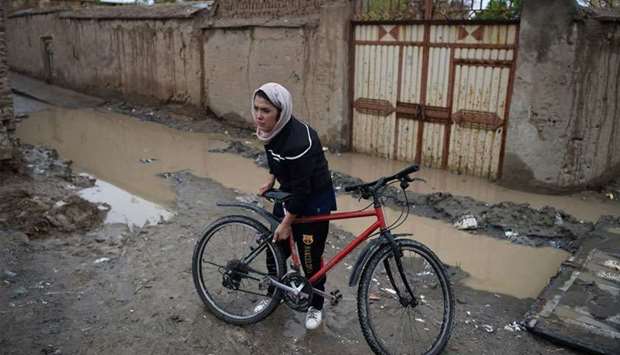Afghan cyclist Kobra Samim adjusts her bicycle on a street in Kabul. Across Afghanistan, women have taken to social media to join a campaign dubbed #MyRedLine that aims to pressure the government, the Taliban and the United States into ensuring women's hard-won advancements are not tossed aside in a rush for a peace accord.