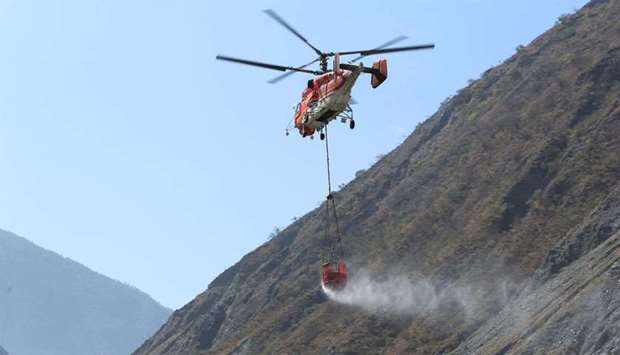 Helicopter carries water in a bucket to extinguish forest fire in Muli county, in Liangshan Yi Autonomous Prefecture, Sichuan