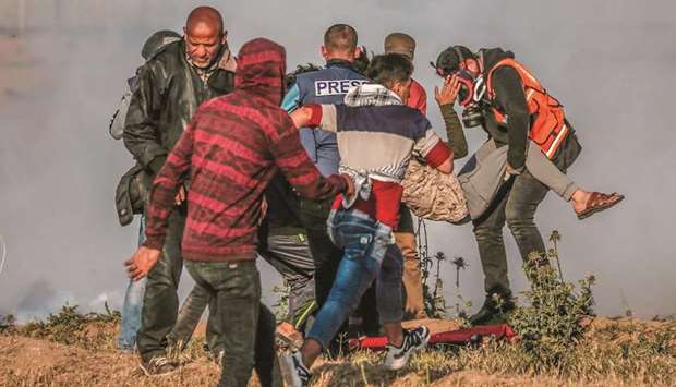 Palestinian paramedics carry an injured protester during clashes with Israeli forces following a demonstration by the border fence with Israel, east of Gaza City, on April 19.