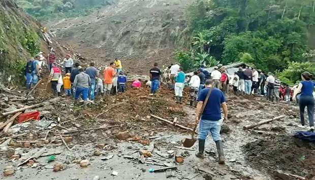 People searching for those who might be trapped under rubble after a mudslide buried eight houses killing at least 14 people and injuring five in the municipality of Rosas, department of Valle del Cauca in southwestern Colombia, yesterday.