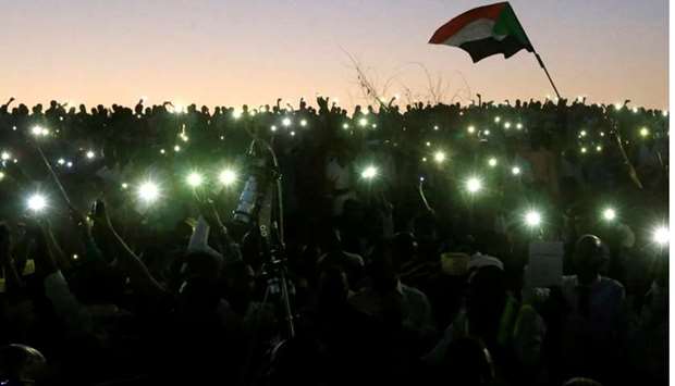 Sudanese demonstrators use their mobile phone torches as lamps as they attend a mass anti-government protest outside the Defence Ministry in Khartoum