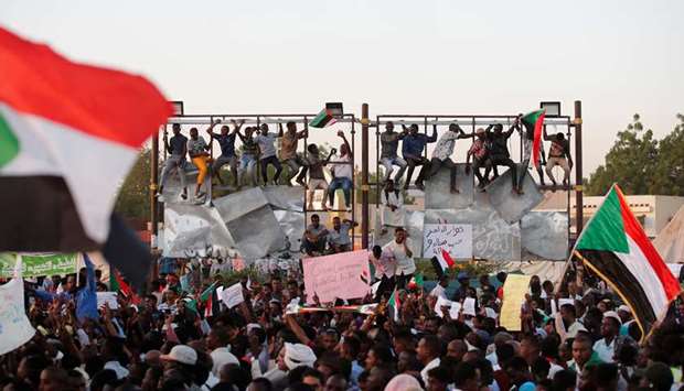 Sudanese protesters wave national flags and shout slogans as they gather for a mass protest in front of the Defence Ministry in Khartoum, yesterday.