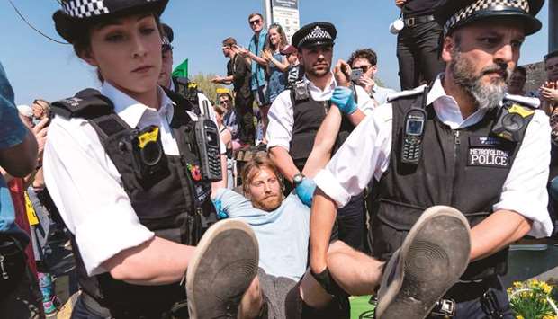 Police officers arrest and carry away a climate change activist from a demonstration blocking Waterloo Bridge in London yesterday.