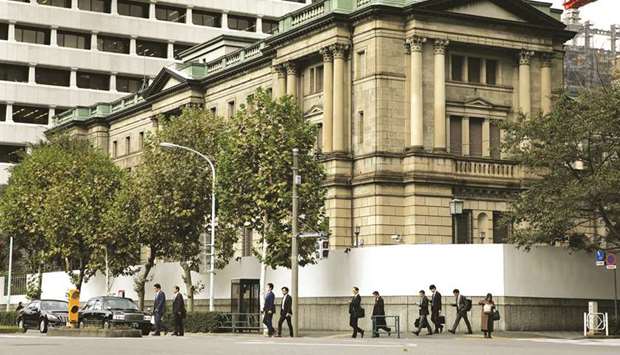 Pedestrians cross a road in front of the Bank of Japan headquarters in Tokyo. About half of economists now expect the BoJu2019s next policy move to be monetary easing, including three who see it coming this week, according to a Bloomberg survey.