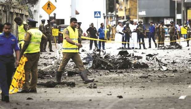 Security personnel inspect the debris of a car after it explodes when police tried to defuse a bomb near St Anthonyu2019s Shrine as priests look on in Colombo yesterday, a day after the series of bomb blasts targeting churches and luxury hotels in Sri Lanka.
