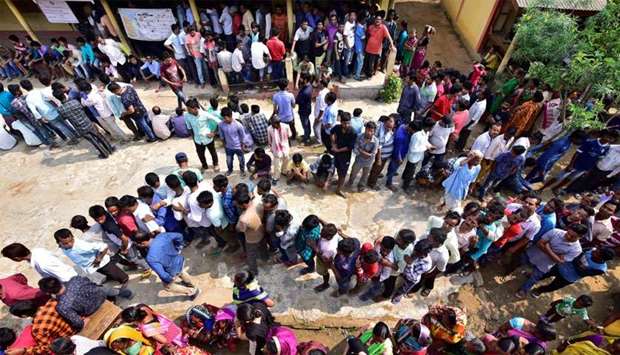 People wait in queues to cast their votes at a polling station during the third phase of general election in Guwahati